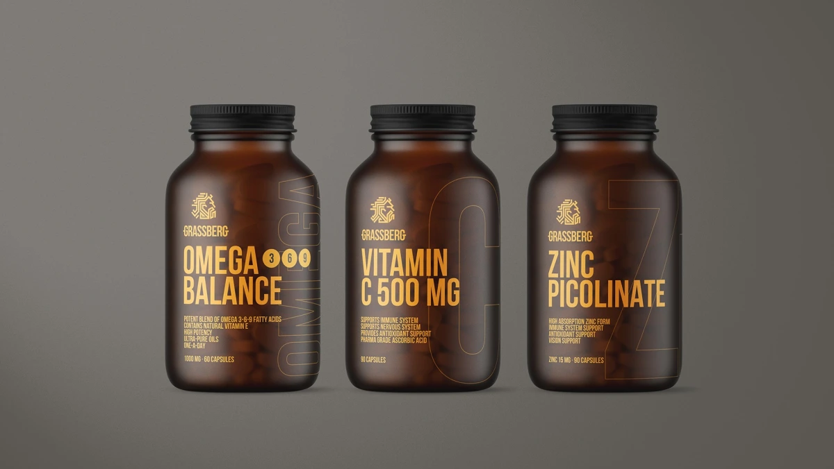 Three Grassberg supplement bottles, Omega Balance, Vitamin C and Zinc Picolinate, in a row