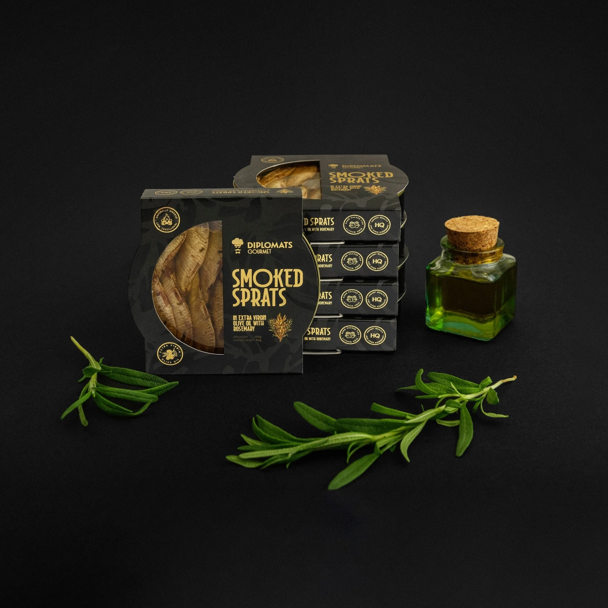 Diplomats Smoked Sprats boxes stacked with olive oil bottle and rosemary sprigs