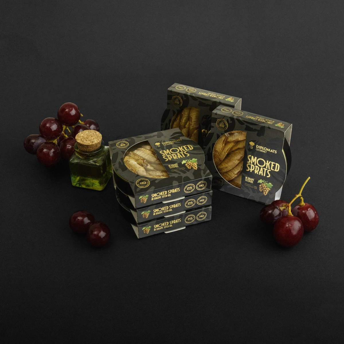 Stacked Smoked Sprats in grape seed oil boxes with grapes and oil bottle