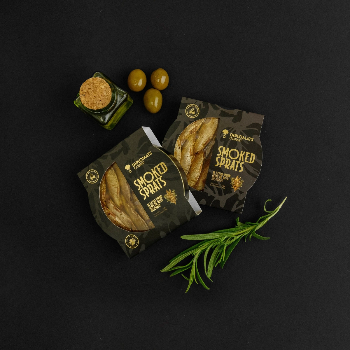 Two Smoked Sprats with rosemary boxes beside olives and rosemary sprig