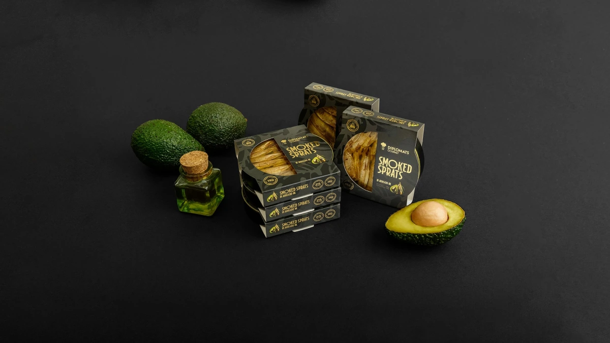 Diplomats Smoked Sprats boxes with olive oil bottle and avocados on black background