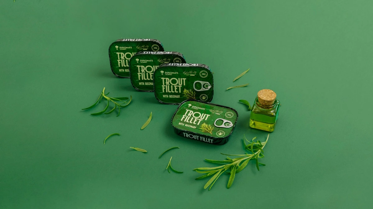 Diplomats Trout Fillet tins with rosemary and oil bottle on green background