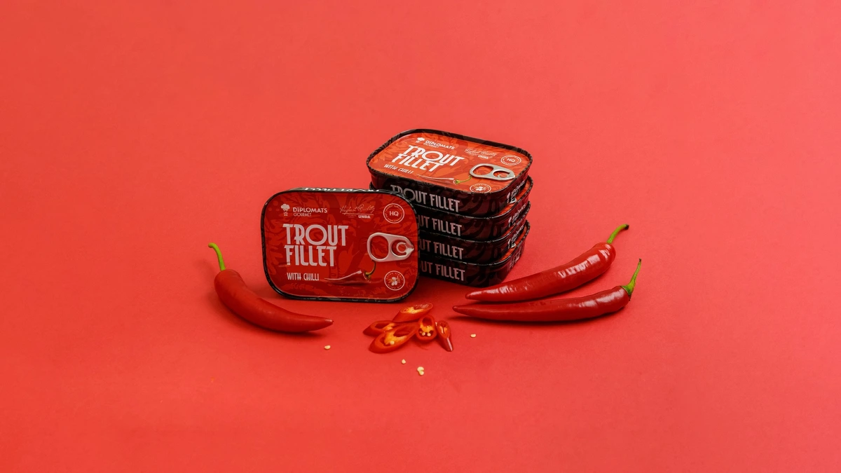 Trout Fillet chilli tins stacked beside whole and chopped red chillies