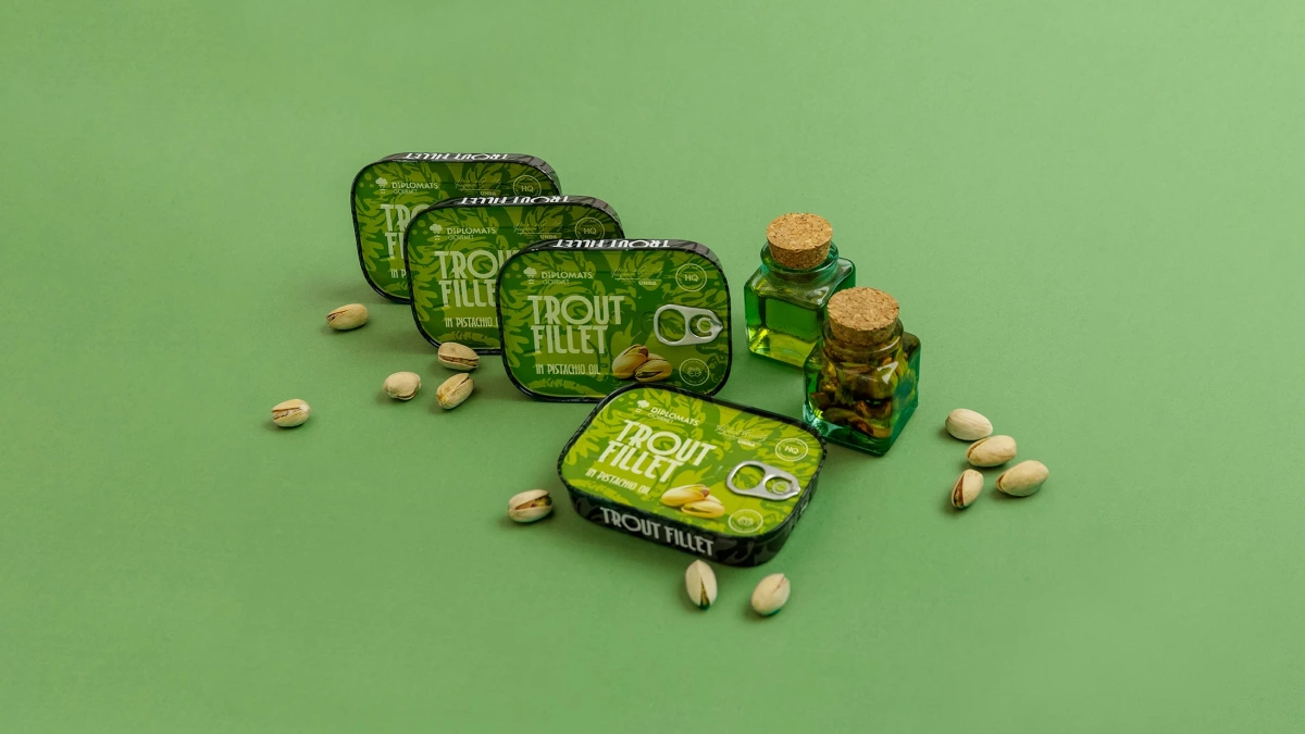 Trout Fillet pistachio oil tins stacked with two oil bottles, pistachios scattered widely