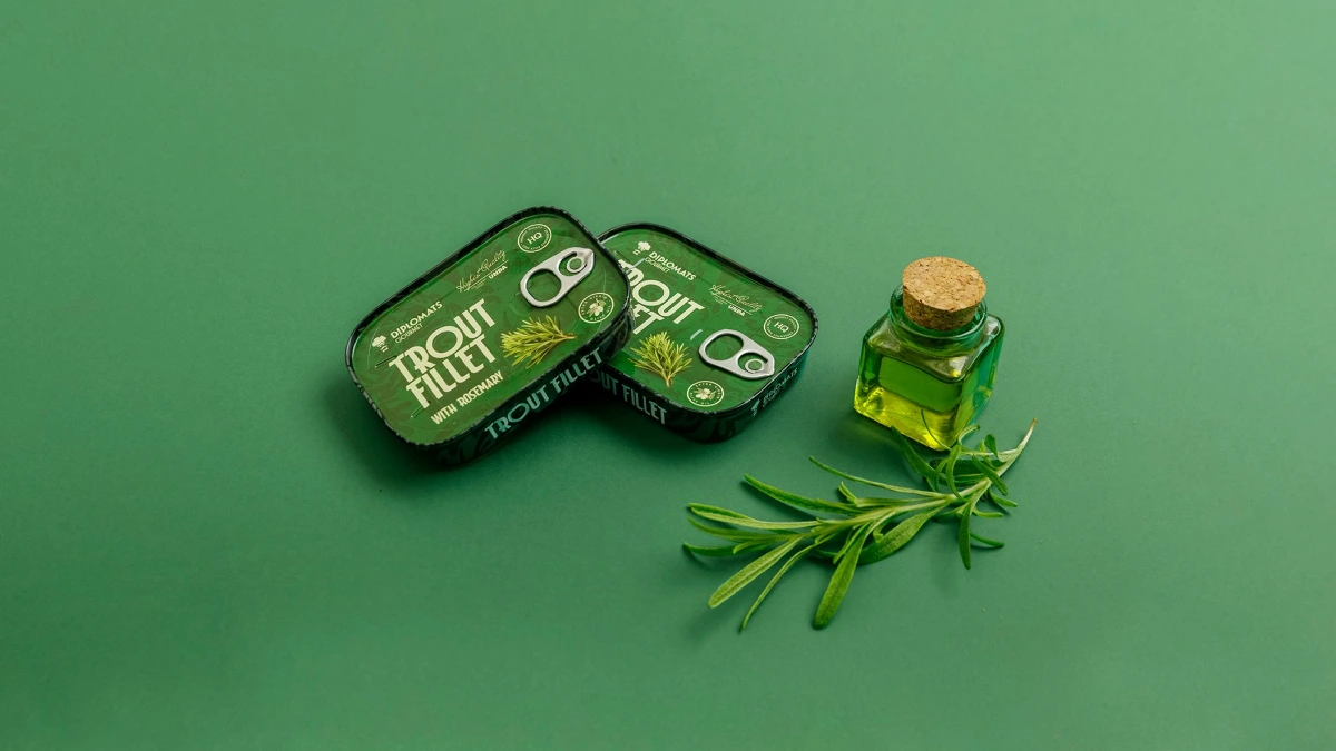 Trout Fillet rosemary tins beside a corked oil bottle and rosemary sprig