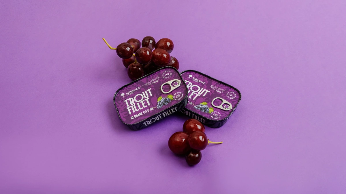 Trout Fillet grape seed oil tins tilted beside bunches of red grapes