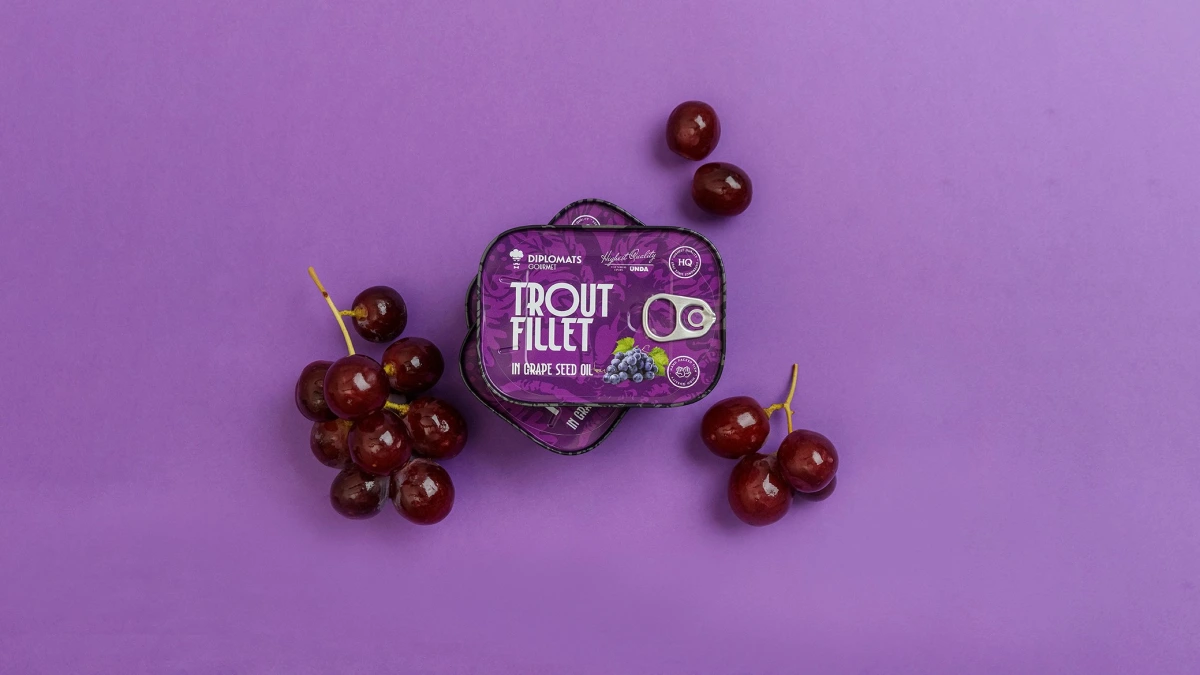 Trout Fillet grape seed oil tin close-up surrounded by loose red grapes