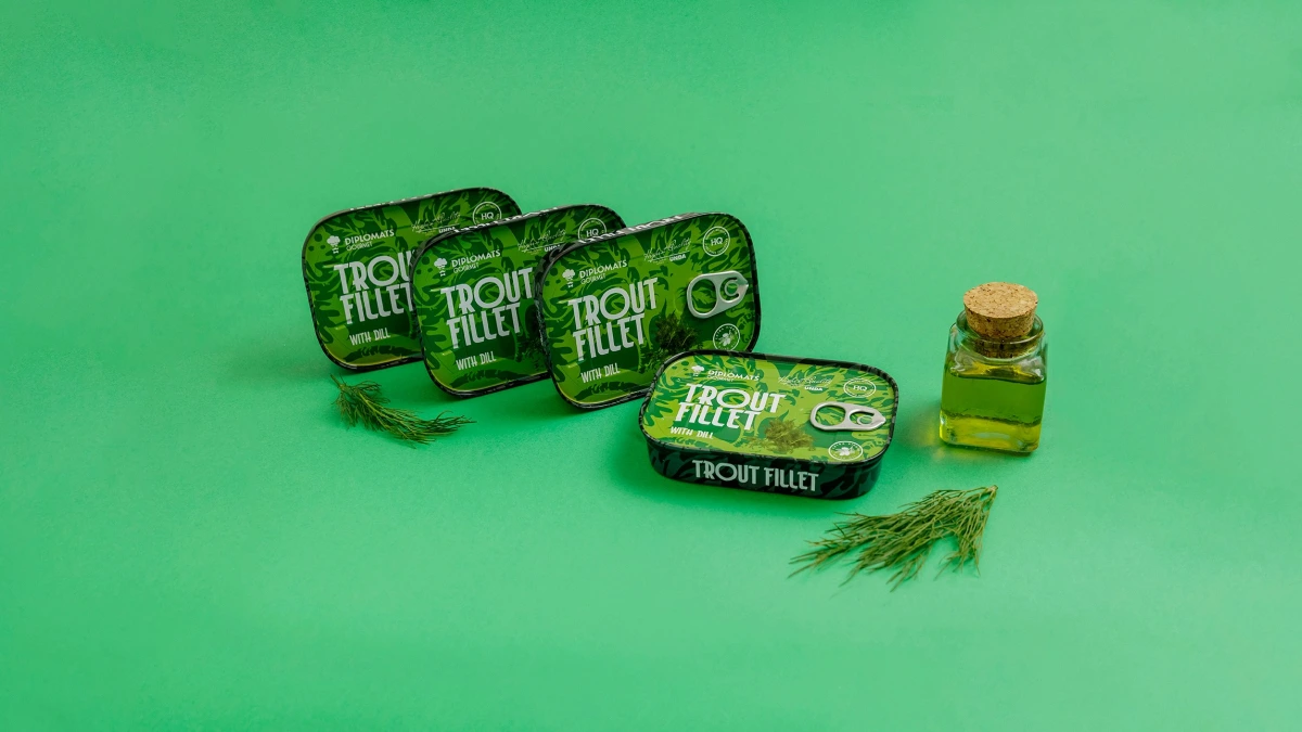 Four Diplomats Trout Fillet tins with dill beside oil bottle on green